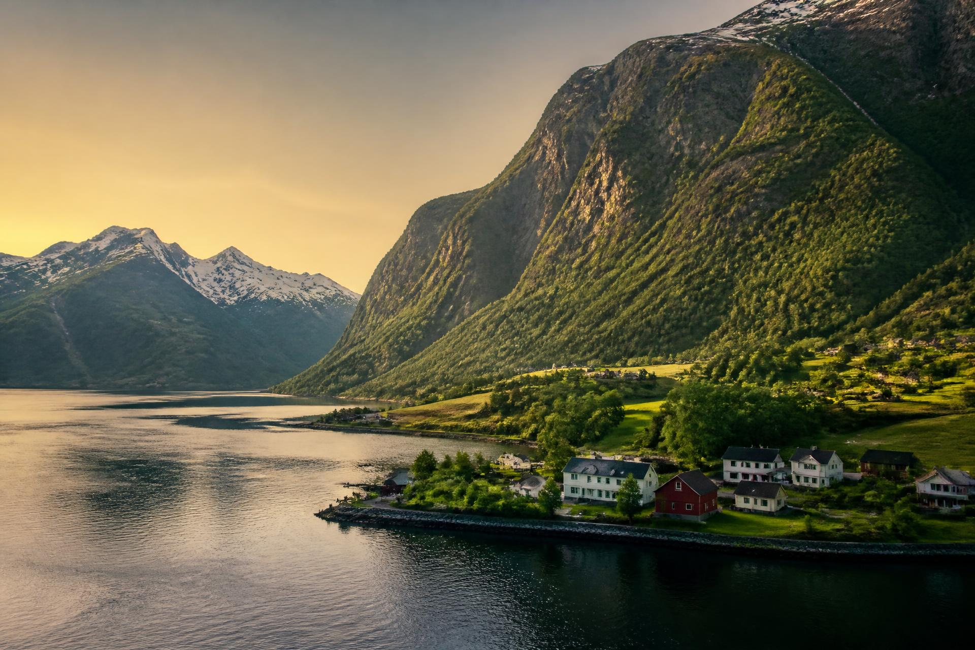 Fiorde norueguês ao amanhecer com montanhas e um pequeno vilarejo à beira da água